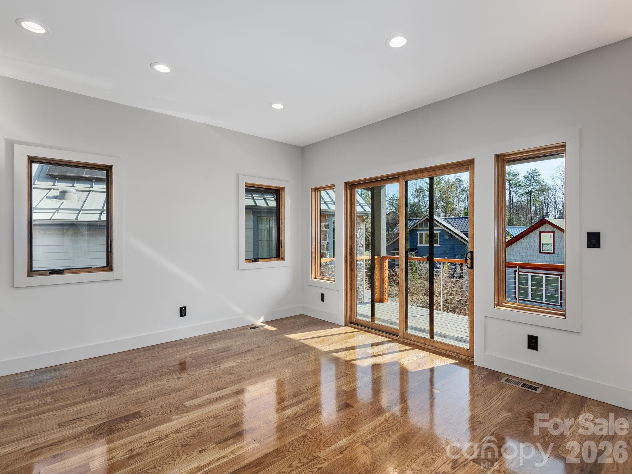 Representative photo from 50 Verde Drive showing the builder’s quality of construction and finish level, including the dining area with oak hardwood floors and large sliding doors opening to the covered deck. - Asheville