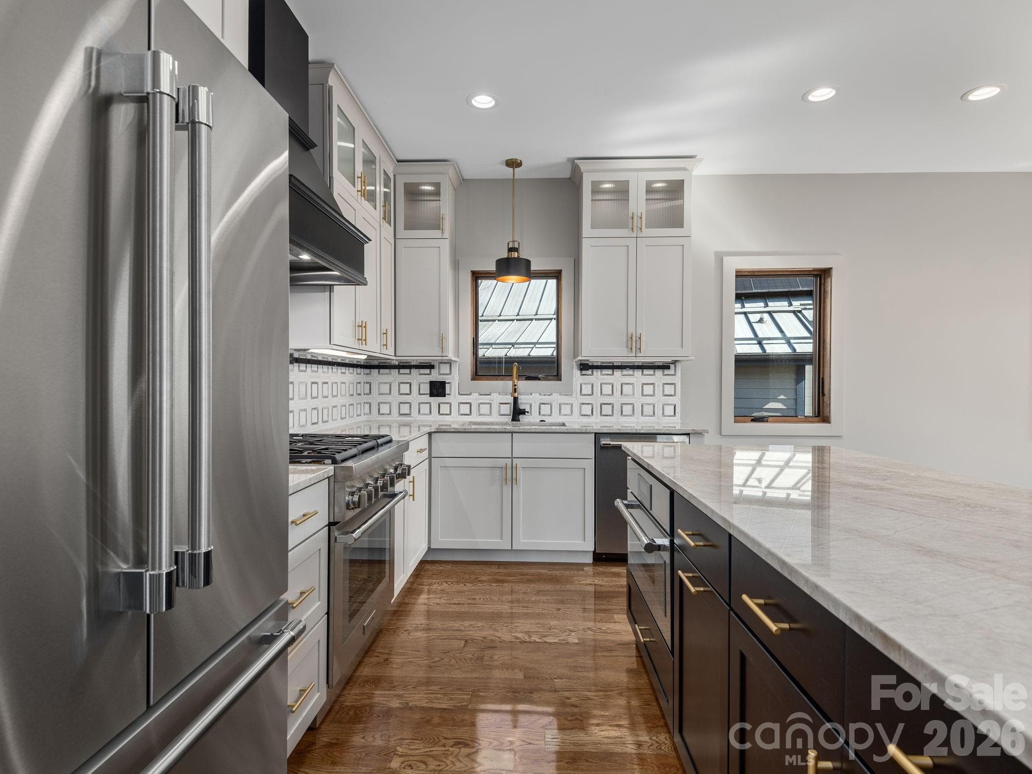 Representative photo from 50 Verde Drive showing the builder’s quality of construction and finish level, including granite countertops, Thermador appliances, Wolf Home Products cabinetry, tile backsplash, and an oversized center island. - Asheville