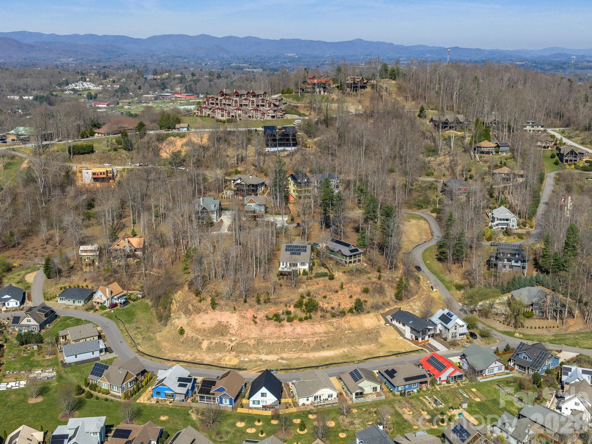 Aerial drone view of The Villages at Crest Mountain and surrounding area, showcasing the community setting and regional mountain backdrop. - Asheville