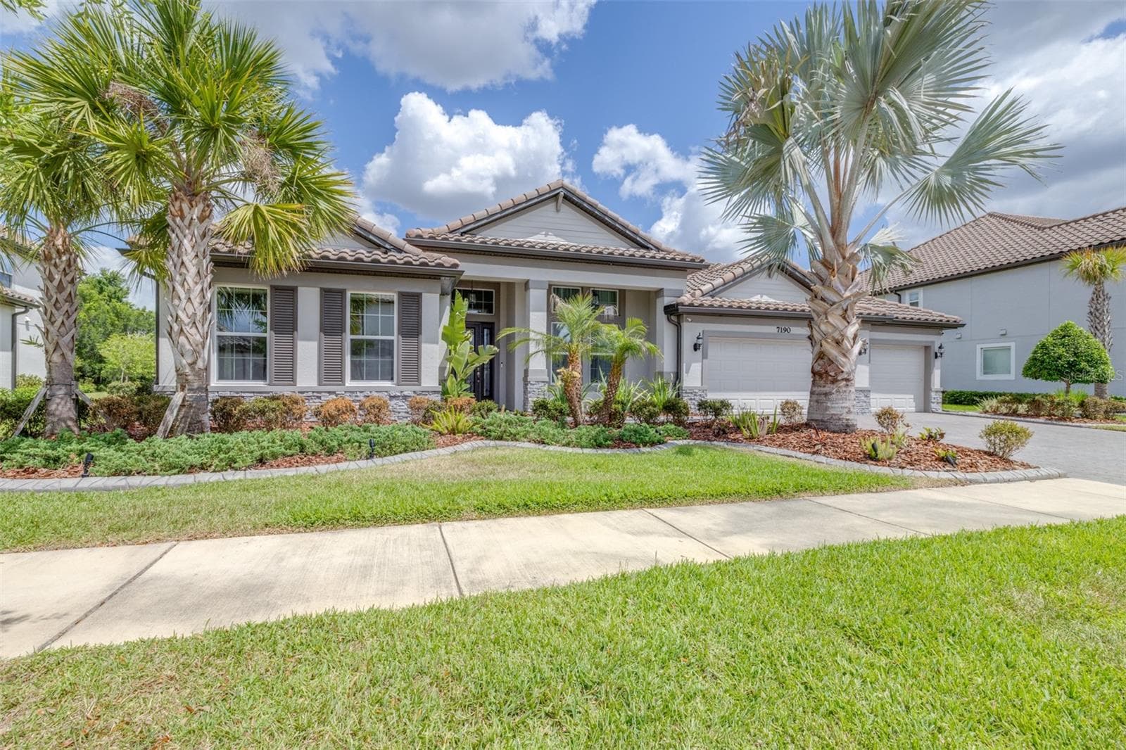 Mature Landscaping and Barrel-Tile Roof Accent the Exterior of the Home - 7190 GRAYBROOK DR, WESLEY CHAPEL