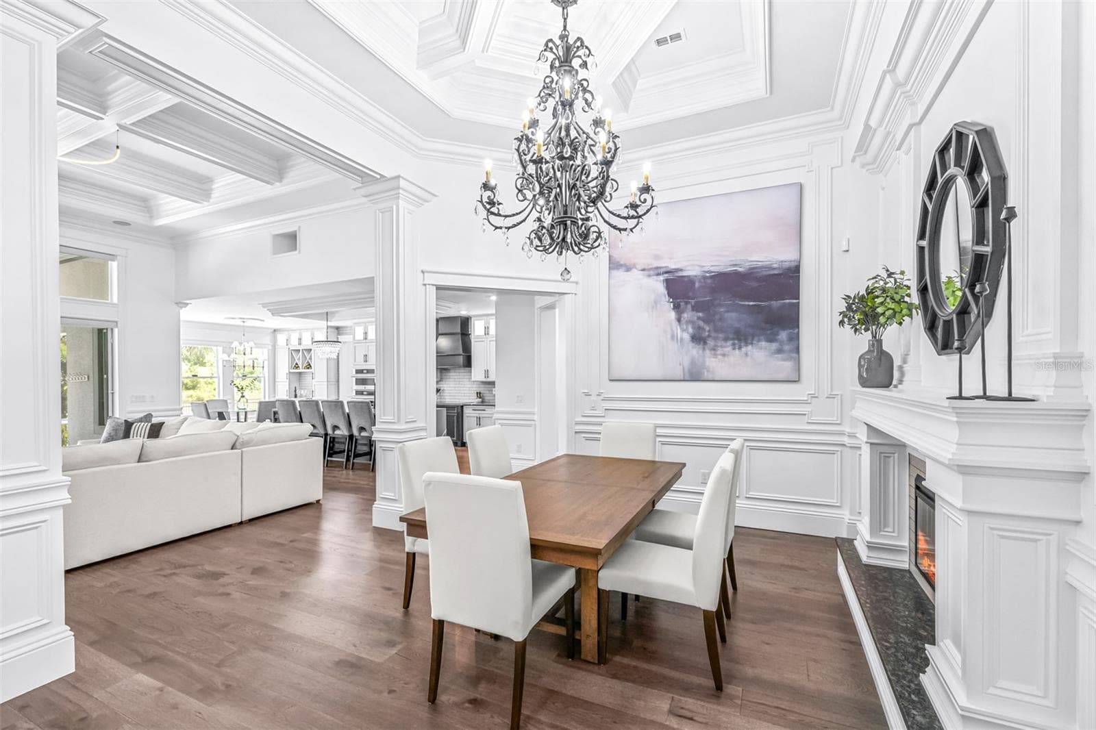 Formal Dining Room is Accented with an Enormous Custom Chandelier, Immaculately Trimmed Columns, an Electric Fireplace with Multiple Settings surrounded by a Tailor-Made Mantle - 7190 GRAYBROOK DR, WESLEY CHAPEL