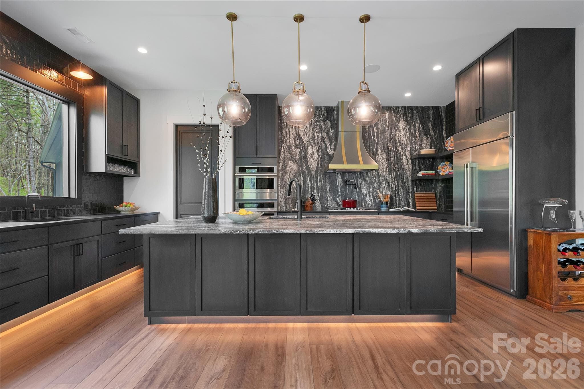 Thoughtfully designed for the culinary enthusiast, the kitchen offers abundant counter space and functions as a natural gathering hub, enhanced by under cabinet floor lighting that creates a soft, inviting ambiance. - Brevard