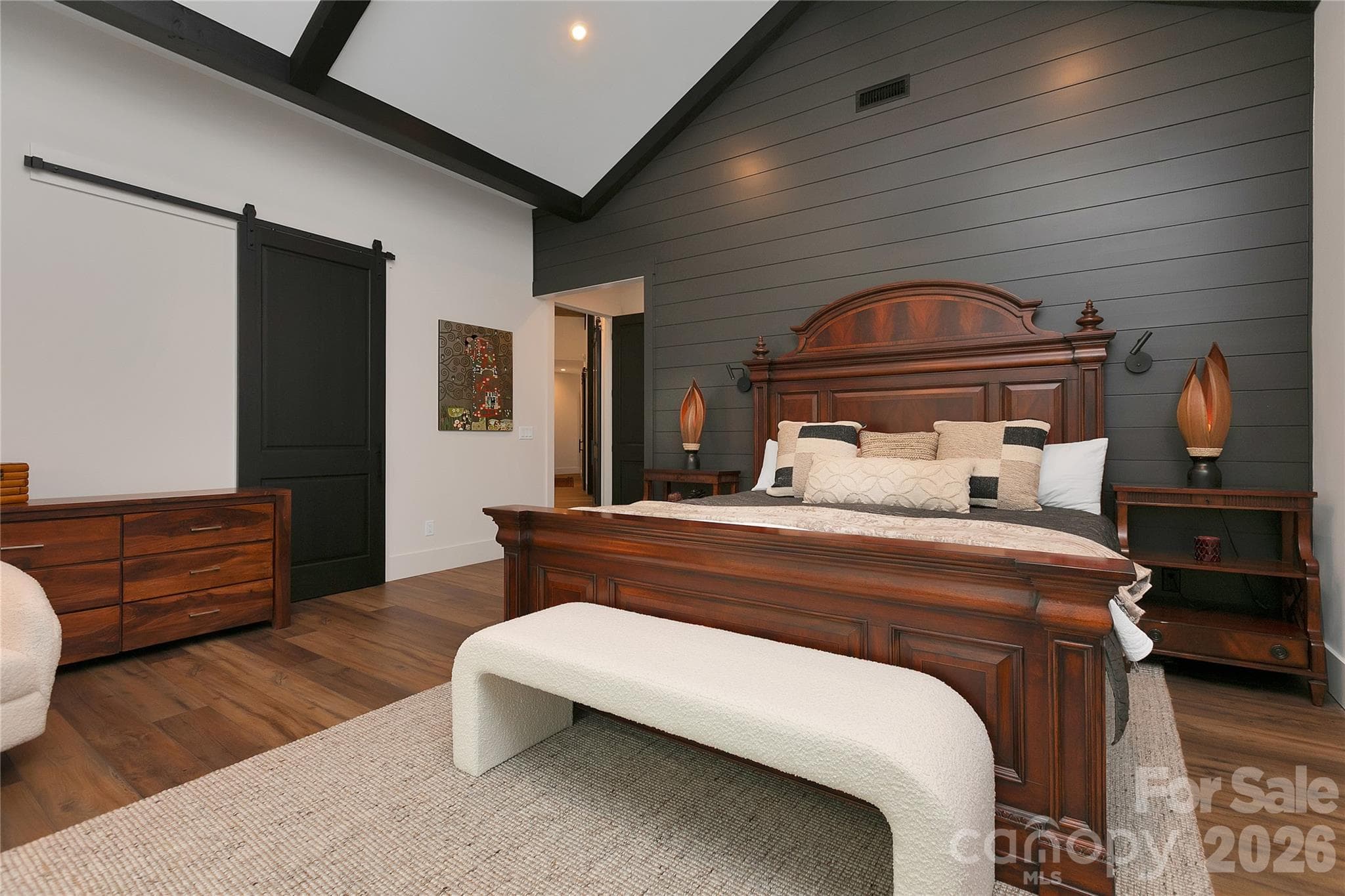 Designed for comfort and visual impact, the primary suite showcases soaring ceilings with striking exposed wood beams. - Brevard