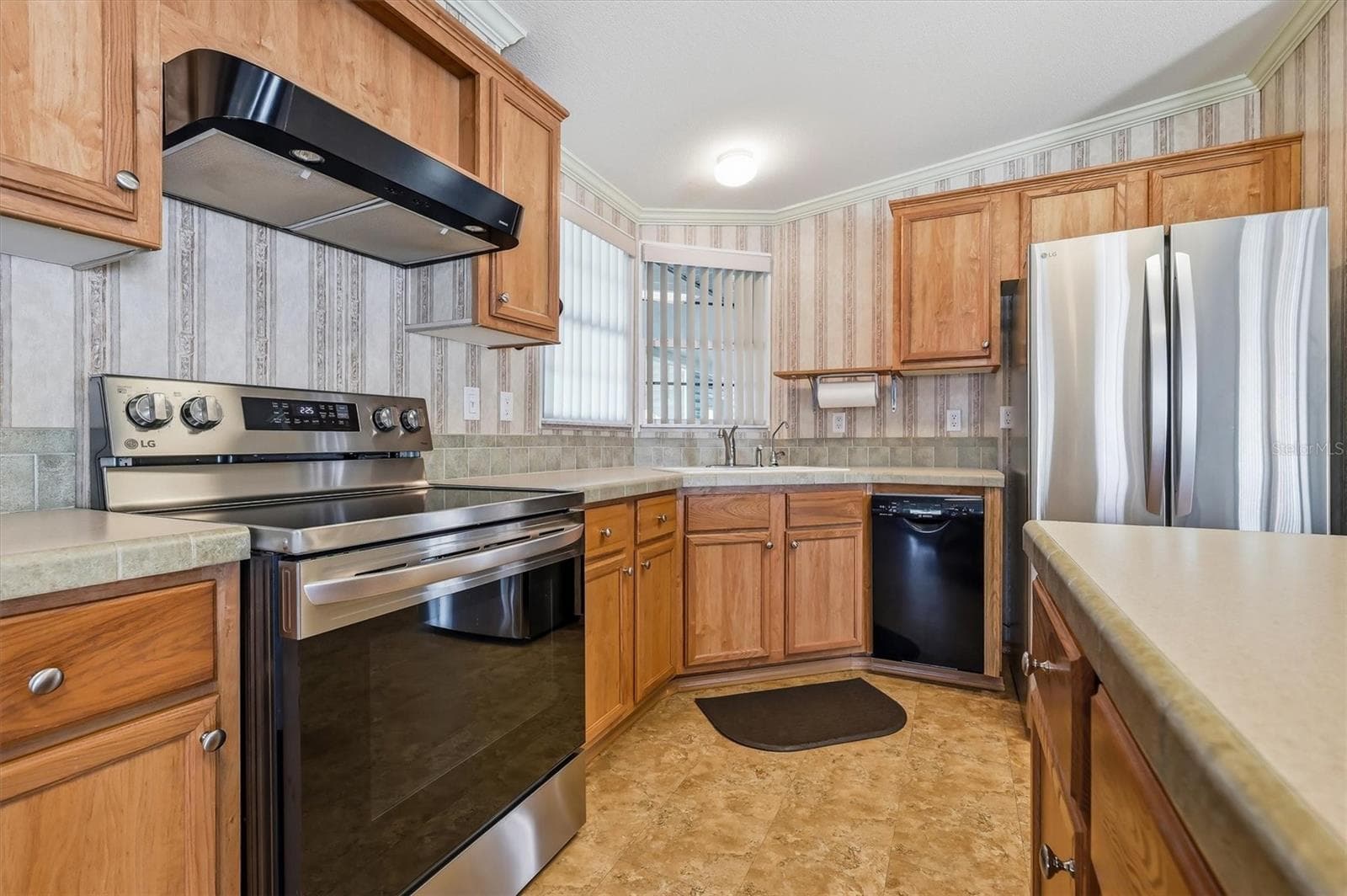 Kitchen features a Corian island top that seats 4, a Corian tiled countertop,  a refrigerator with ice maker & water, a Culligan RO system at the sink for water, and a stove with a convection oven feature - 10027 EQUITY AVE, DADE CITY