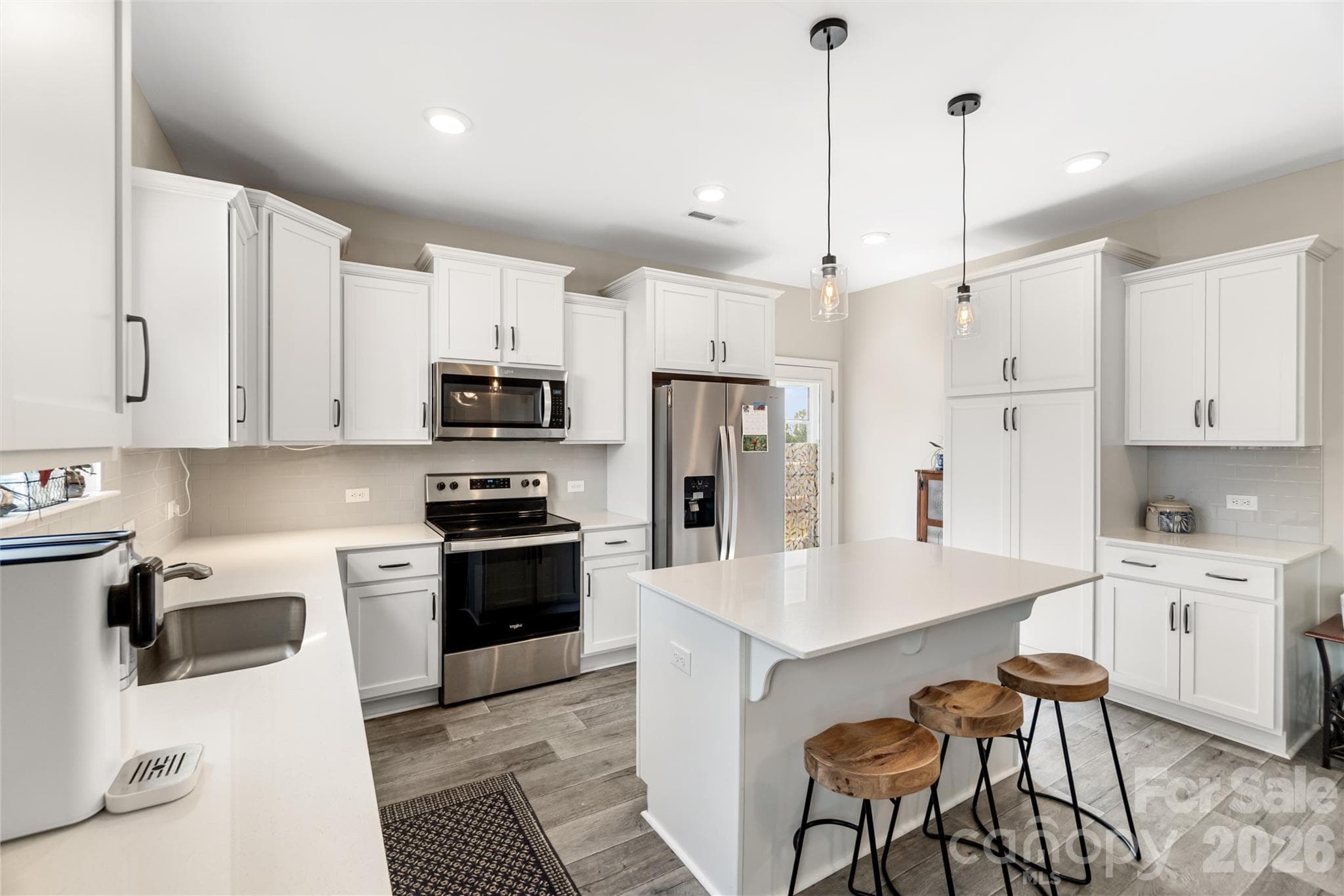 Stylish kitchen features quartz countertops, tile backsplash, stainless steel appliances, and ample cabinetry for storage. - 43 Cobbler Drive, Peachland