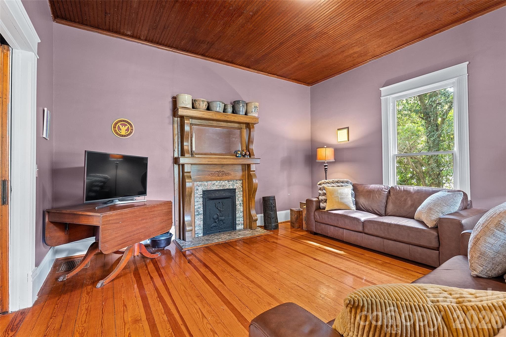 Quaint family room with wood mantel with elegant curved detailing, complemented by a classic tiled surround and decorative cast iron insert—adding timeless character and warmth to the space. - 602 N Main Street, Davidson