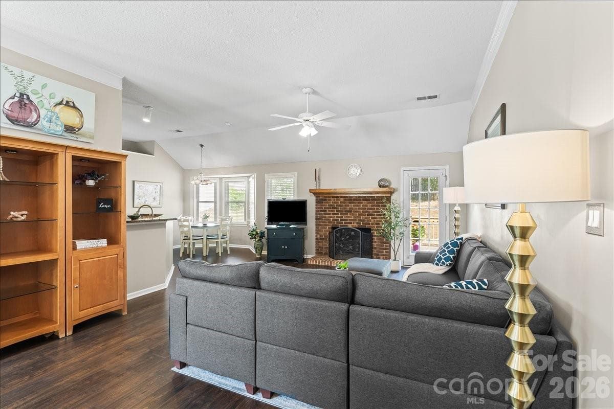 Generous living space with sightlines into the breakfast area and kitchen, stately brick wood burning fireplace and french door to the back deck - Charlotte