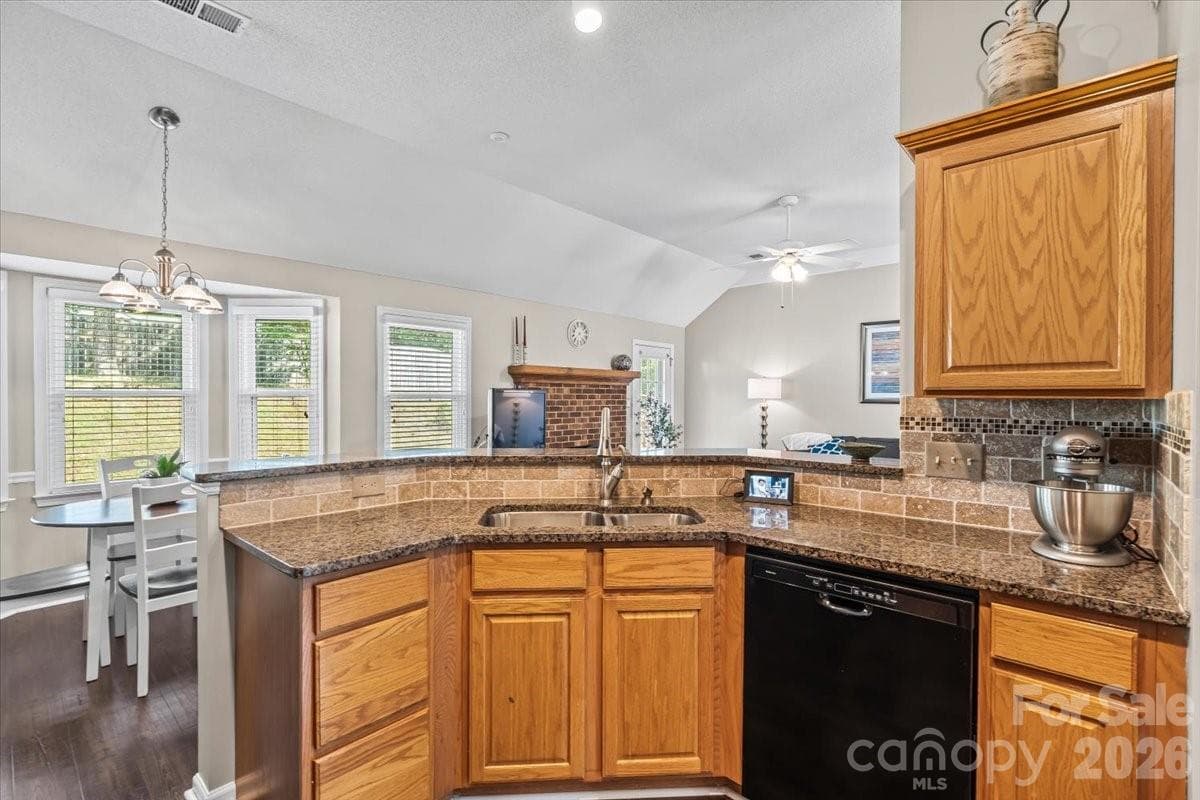 The kitchen anchors the home with granite countertops, tile backsplash, and a breakfast bar peninsula - Charlotte