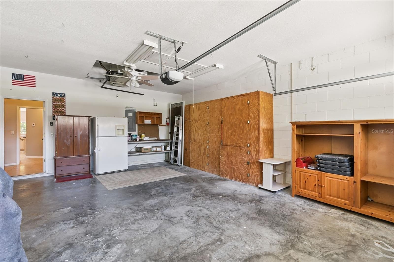 Oversized garage with built-in shelves and pull-down ladder system for attic access and additional storage. - 237 STRATHMORE CIR, KISSIMMEE
