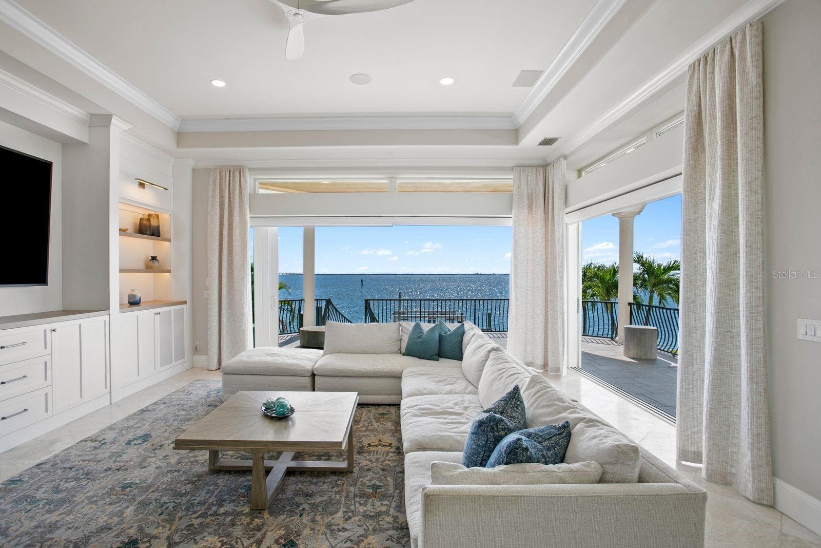 Another stunning perspective of the family room showcasing the fully opened sliders and seamless indoor-outdoor living. - 611 1ST AVE S, TIERRA VERDE