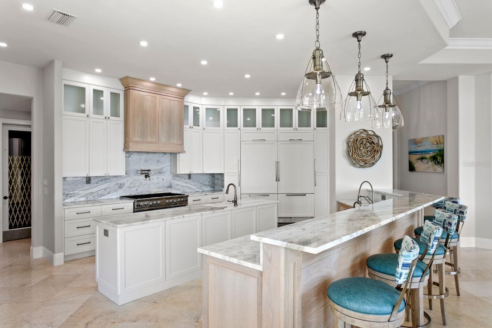 An elegant chef's kitchen appointed with quartz surfaces and statement designer lighting. - 611 1ST AVE S, TIERRA VERDE
