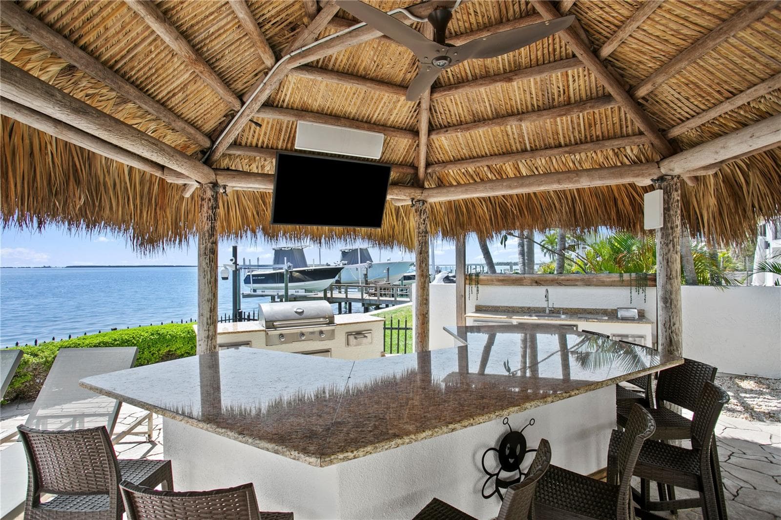 Outdoor kitchen with bar, tiki hut and TV. - 611 1ST AVE S, TIERRA VERDE