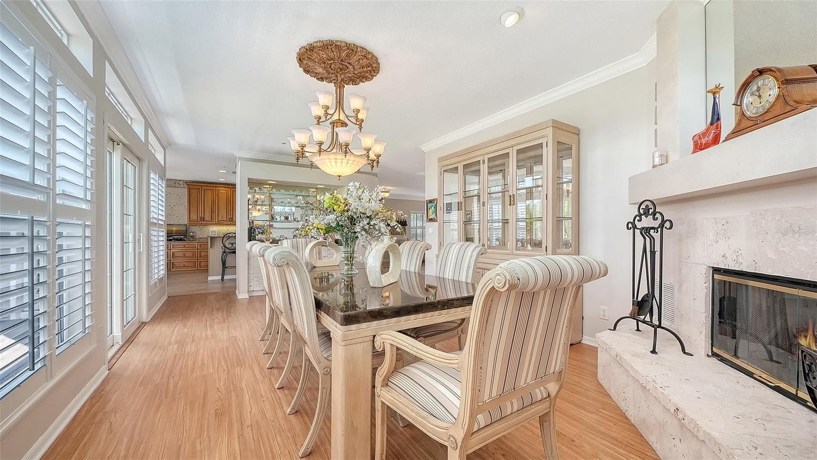 Electric fireplace graces an oversized dining room with complimentary plantation shutters. - 3040 GULF OF MEXICO DR #3, LONGBOAT KEY