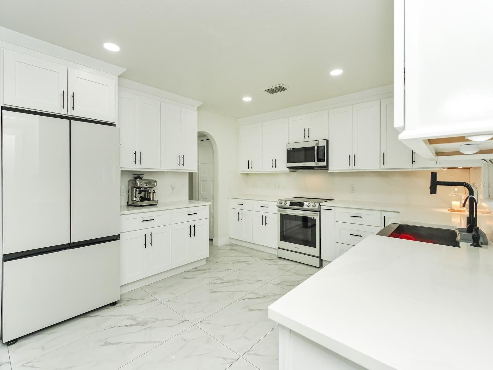 the kitchen counter tops are quartz with a quartz backsplash and soft closed cabinets that are dressed with crown molding and on top and bottom of the cabinets. - 7561 LAKE ANDREA CIR, MOUNT DORA