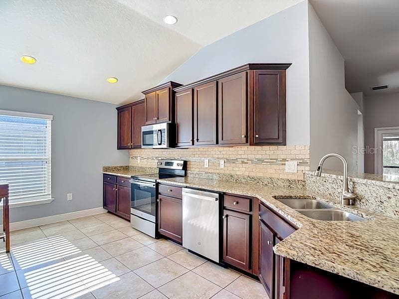Beautifully updated kitchen featuring rich espresso cabinetry, granite countertops, and a coordinating tile backsplacsh. - 12244 LOOPBACK DR, SAN ANTONIO