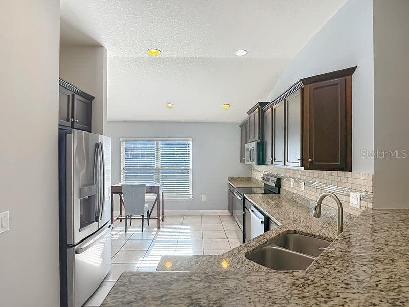 Spacious granite countertop bar area seamlessly overlooks the kitchen and opens to the living room, creating an inviting flow for entertaining and everyday living. - 12244 LOOPBACK DR, SAN ANTONIO