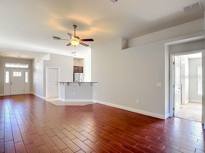 An open-concept living area featuring wood-look flooring and high ceilings that enhance the sense of space and light - 12244 LOOPBACK DR, SAN ANTONIO