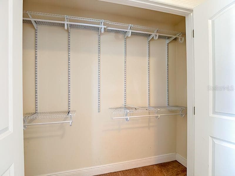 Bedroom 2- a well organized bedroom closet featuring adjustable wire shelving and dual hanging racks, offering flexible storage for clothing and accessories. - 12244 LOOPBACK DR, SAN ANTONIO