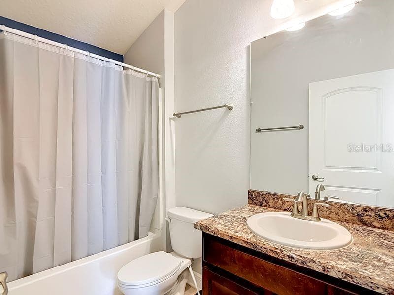 Well-appointed guest bathroom featuring luxury vinyl countertops, neutral tones and clean lines creating a fresh, inviting space for guests conveniently located between the guest bedrooms. - 12244 LOOPBACK DR, SAN ANTONIO