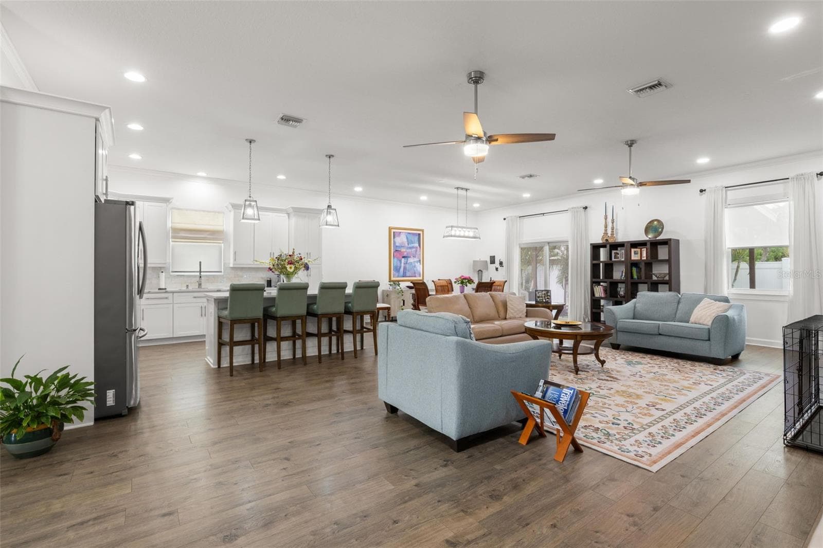 The expansive open-concept layout features wide-plank luxury vinyl flooring, recessed lighting, crown molding, and seamless flow between the great room, dining area, and chef-inspired kitchen. High ceilings and abundant natural light enhance the airy feel, while oversized impact windows and sliding glass doors bring the outdoors in. - 1720 VERDE DR, CLEARWATER