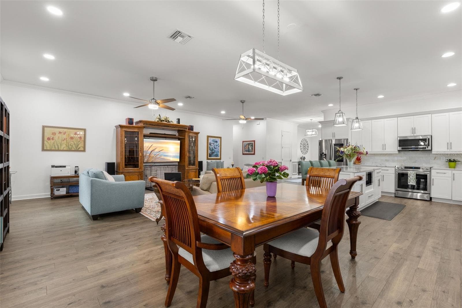The spacious dining area flows effortlessly into the great room and kitchen, creating an open, cohesive layout enhanced by luxury vinyl flooring, recessed lighting, crown molding, and modern designer fixtures. - 1720 VERDE DR, CLEARWATER
