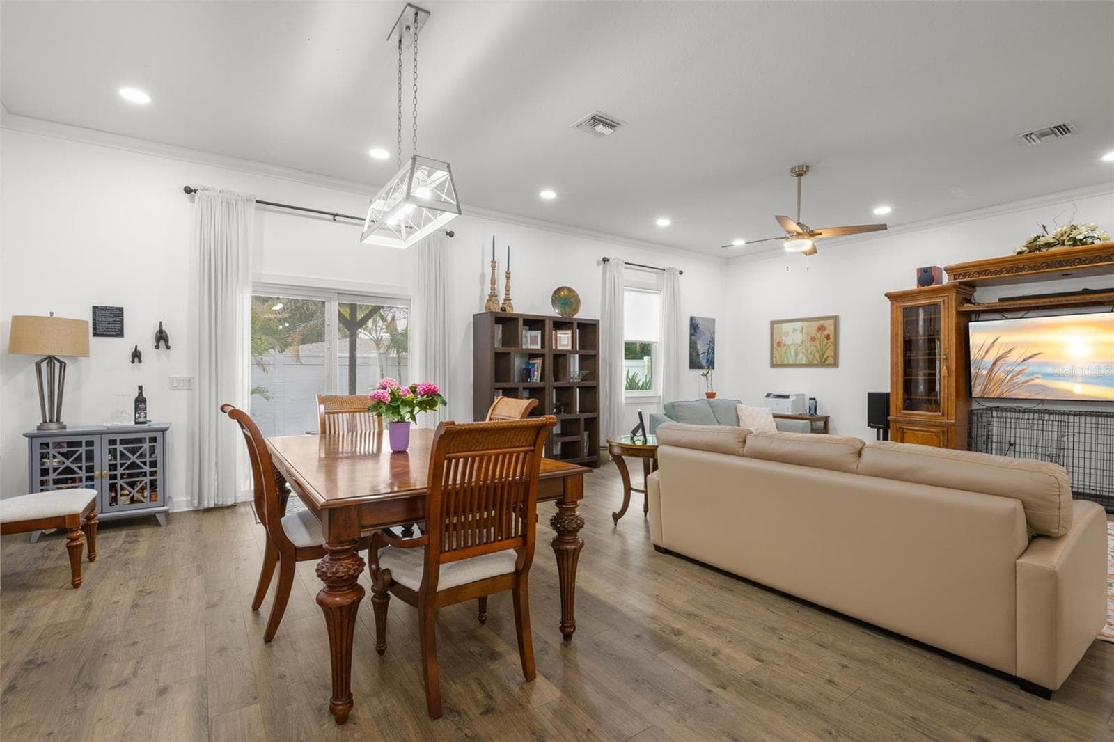 Oversized impact sliding glass doors and large windows fill the dining and living areas with natural light, complementing the home’s high ceilings, crown molding, recessed lighting, and wide-plank luxury vinyl flooring. The open layout offers generous wall space and flexible furniture placement throughout the main gathering areas. - 1720 VERDE DR, CLEARWATER