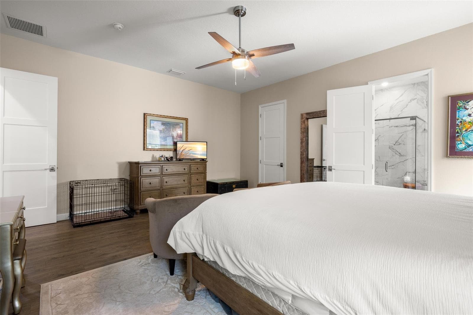 The generously sized primary suite offers a spacious layout with wide-plank luxury vinyl flooring, neutral finishes, oversized paneled doors, and a contemporary ceiling fan. The private ensuite bath features designer tile finishes, while the oversized walk-in closet provides substantial storage space. - 1720 VERDE DR, CLEARWATER