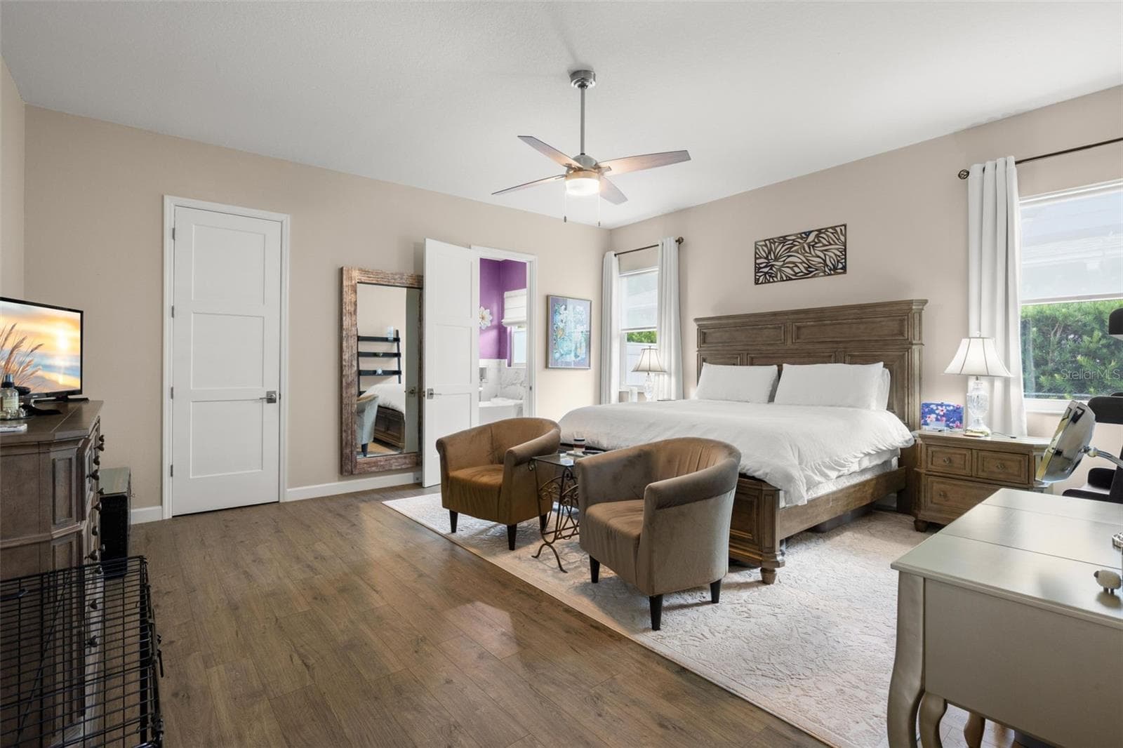 The oversized primary bedroom features wide-plank luxury vinyl flooring, neutral finishes, oversized paneled doors, and a contemporary ceiling fan. With room for a sitting area and direct access to the ensuite bath and walk-in closet, the spacious layout offers both comfort and functionality. - 1720 VERDE DR, CLEARWATER