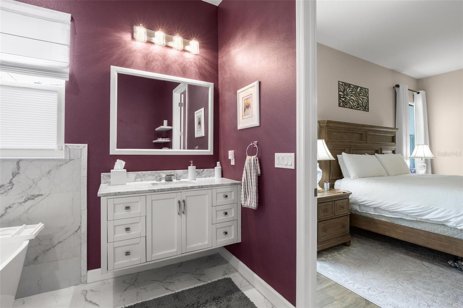 The beautifully appointed primary bath includes designer quartz countertops, upgraded shaker-style vanity cabinetry, contemporary lighting, upgraded plumbing fixtures, and dramatic marble-look tile flooring and wall accents. The spacious ensuite layout flows seamlessly from the primary bedroom, creating a refined private retreat. - 1720 VERDE DR, CLEARWATER