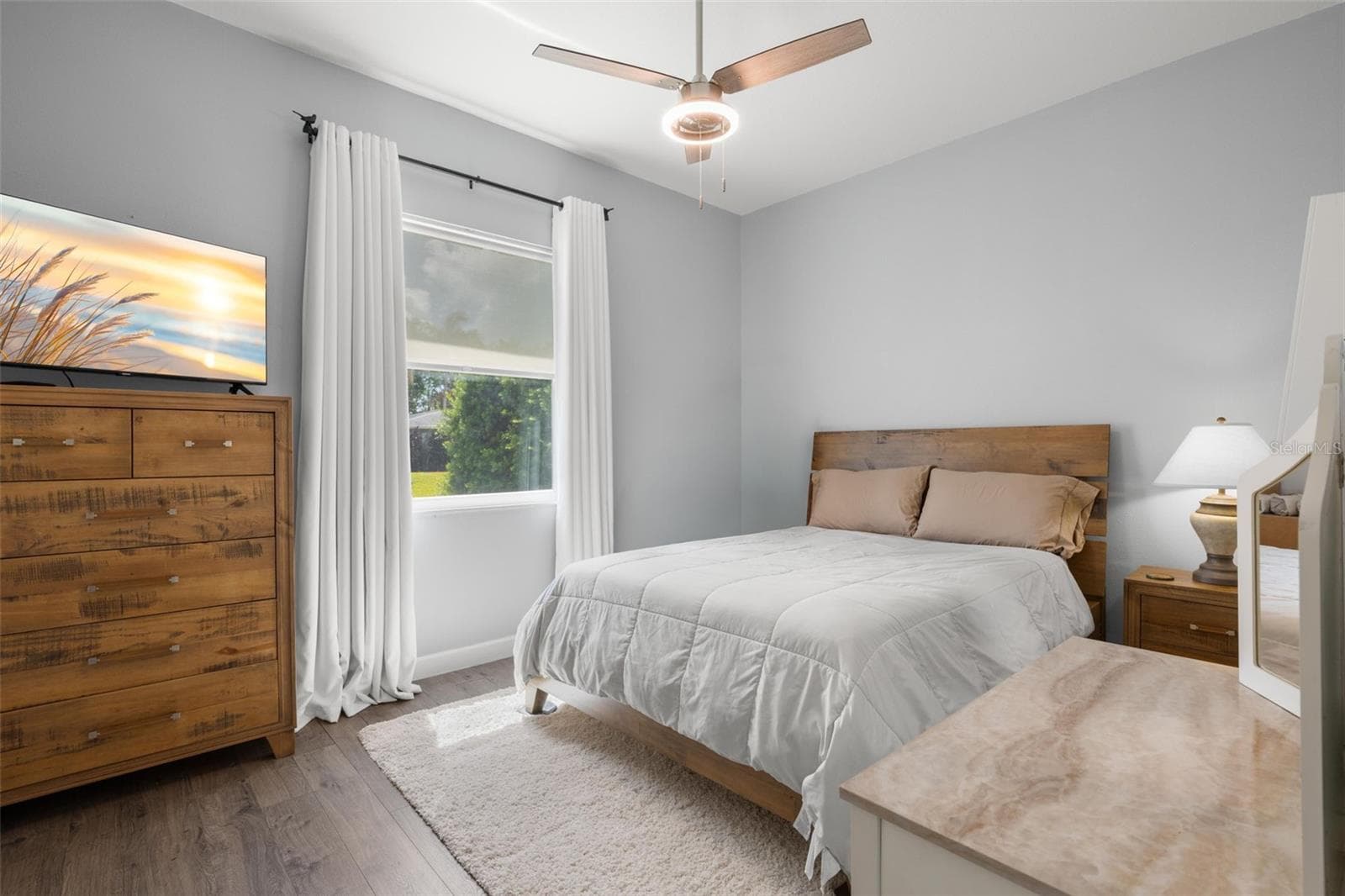 Bedroom 2 features wide-plank luxury vinyl flooring, a contemporary ceiling fan, abundant natural light, and a soft neutral color palette. - 1720 VERDE DR, CLEARWATER