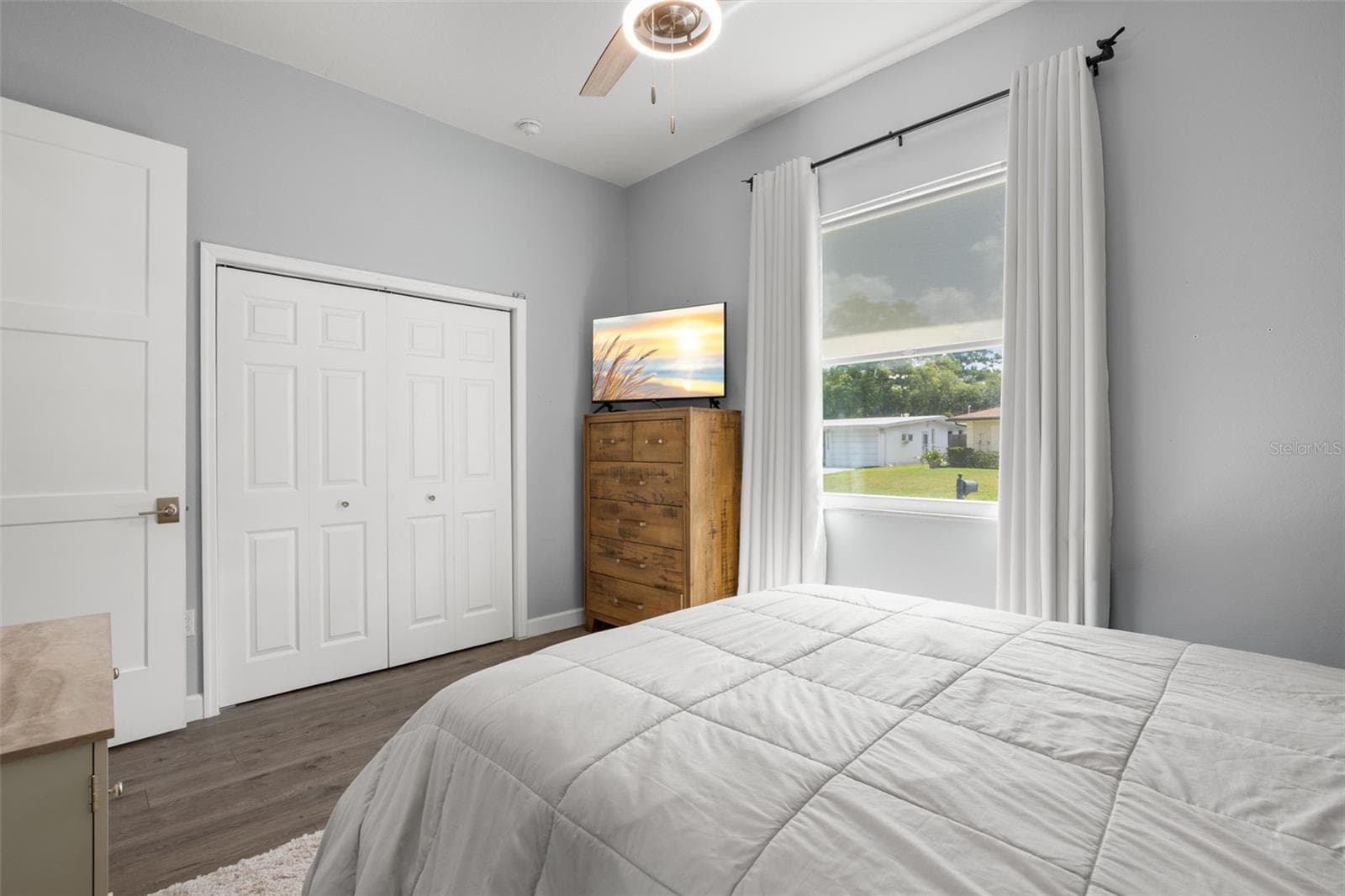 Bedroom 2 features wide-plank luxury vinyl flooring, a built-in closet, a contemporary ceiling fan, and abundant natural light. - 1720 VERDE DR, CLEARWATER