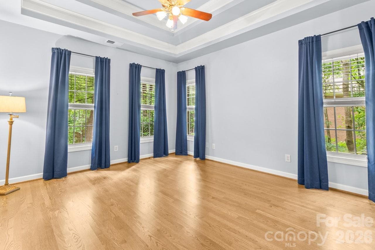 Primary bedroom features wood flooring and tray ceiling. - 4415 Everclear Court, Charlotte