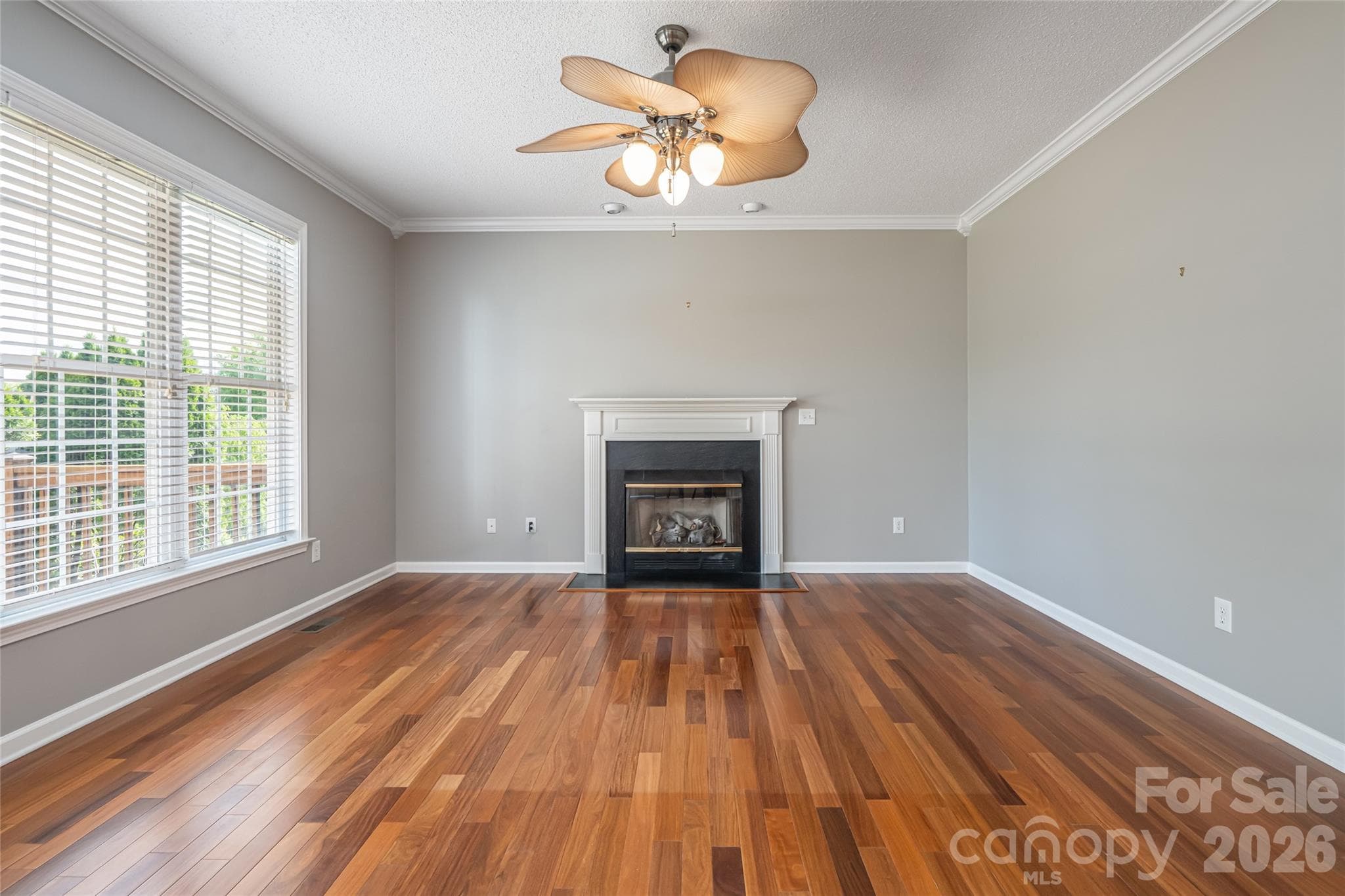 Family room as-is: gas-log fireplace, hardwood floors, ceiling fan, open floor plan to kitchen. - Fletcher