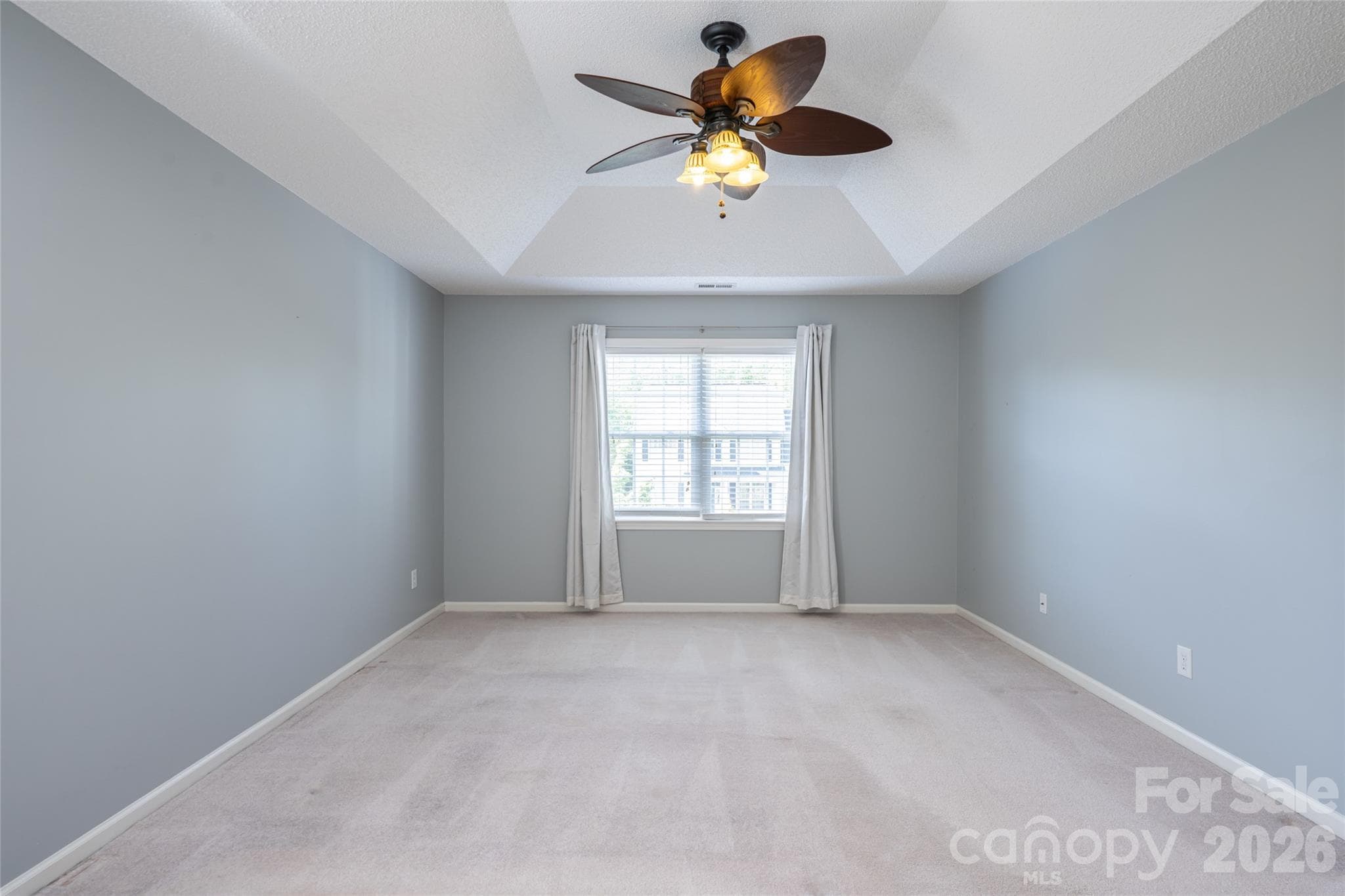 Primary bedroom as-is: tray ceiling, ceiling fan, carpet, natural light. - Fletcher