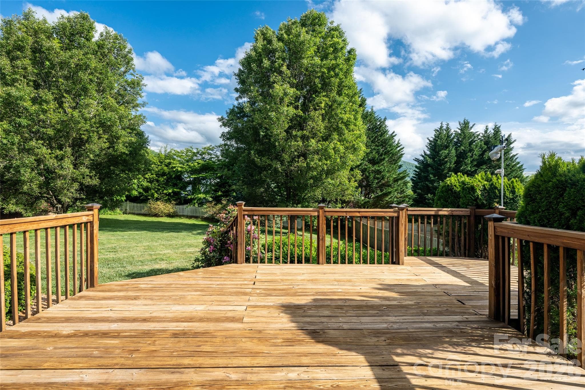 Rear deck as-is, looking over the backyard toward the tree line and green space border. - Fletcher