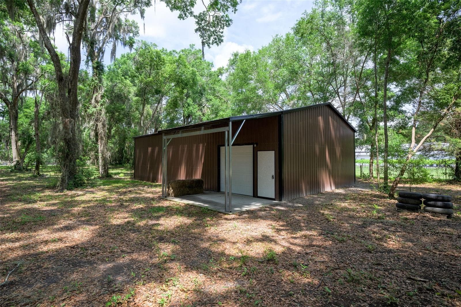 30x50 workshop with a concrete floor, power, shop lights, and multiple outlets. The shop includes two powered bay doors—one 8x8 and one 10x10—and a covered porch, making it ideal for vehicles, equipment, or a home-based business. - 374 SISCO RD, POMONA PARK