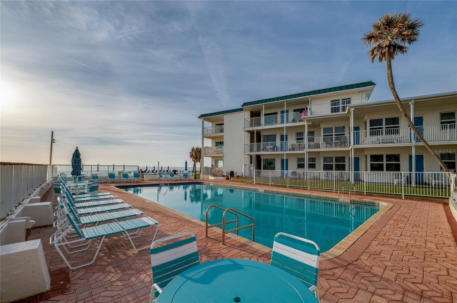 Large, crystal-clear swimming pool surrounded by a spacious sun deck with premium lounge chairs. The ocean breeze and panoramic views create a true vacation atmosphere. - 935 S ATLANTIC AVE #165, DAYTONA BEACH