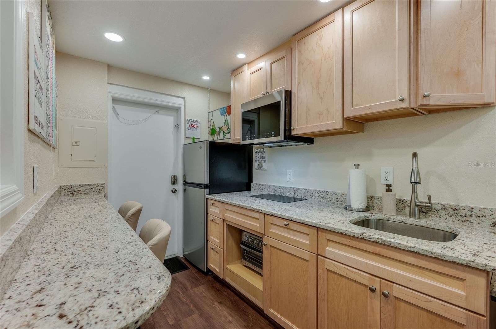 Efficient kitchen featuring a full-sized refrigerator, sleek cabinetry, and a microwave. - 935 S ATLANTIC AVE #165, DAYTONA BEACH