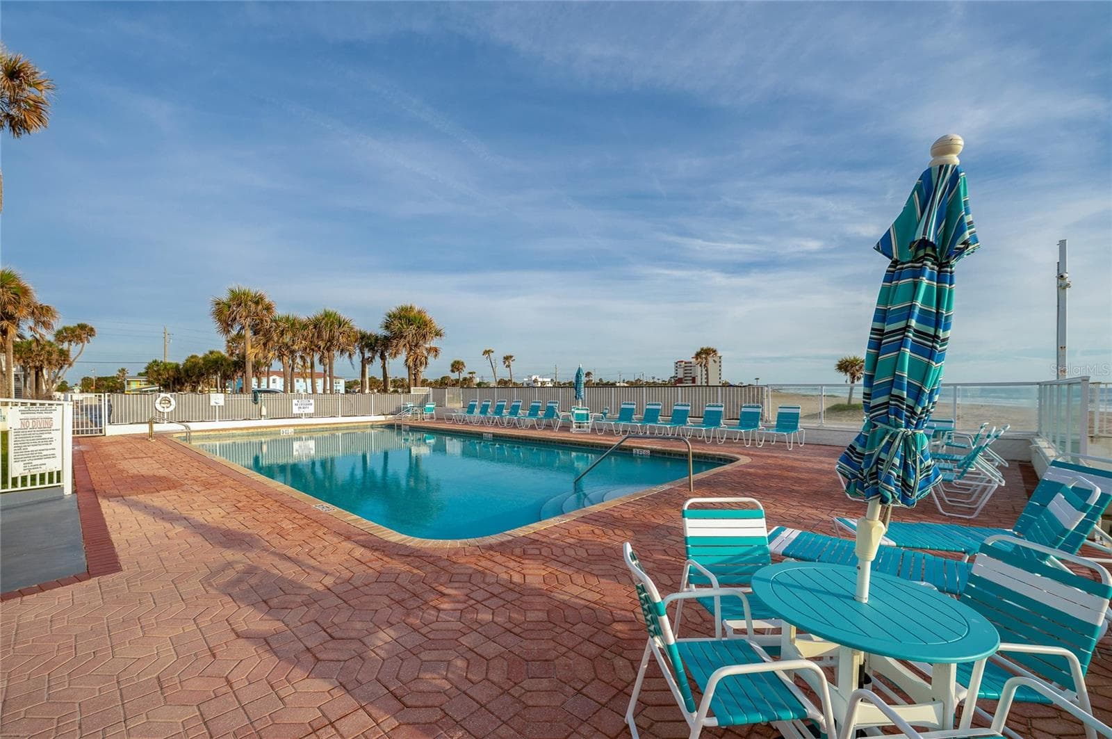 Secondary pool view featuring vibrant teal patio furniture and umbrellas, emphasizing the resort’s commitment to guest comfort and a lively coastal aesthetic. - 935 S ATLANTIC AVE #165, DAYTONA BEACH