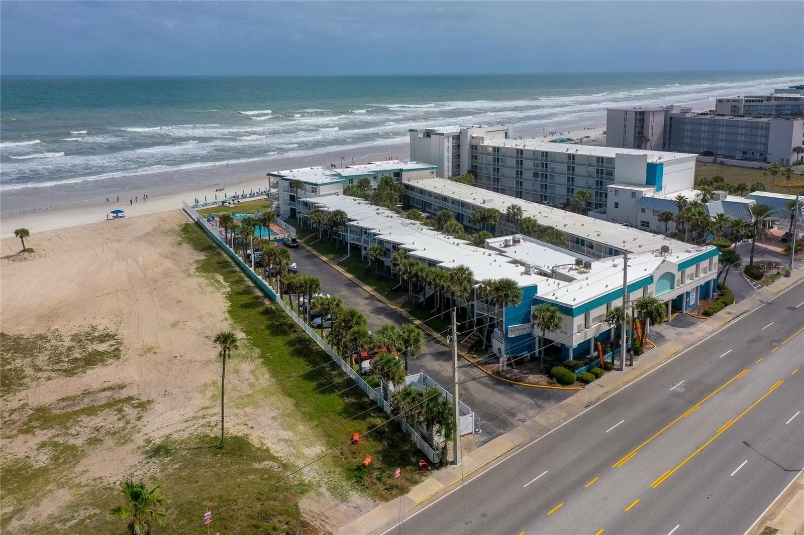 Wide-angle coastal shot highlighting the building’s footprint relative to the surf, emphasizing the premium placement within this sought-after oceanfront community. - 935 S ATLANTIC AVE #165, DAYTONA BEACH