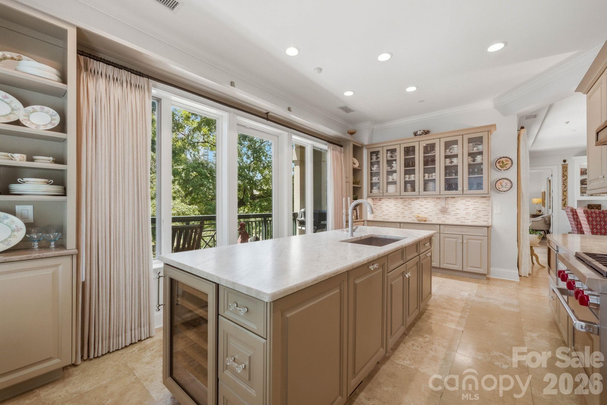 Beautifully designed chef’s kitchen featuring custom cabinetry, natural stone countertops, premium appliances, and an oversized island perfect for entertaining. Expansive windows fill the space with natural light and overlook the private terrace. - Charlotte