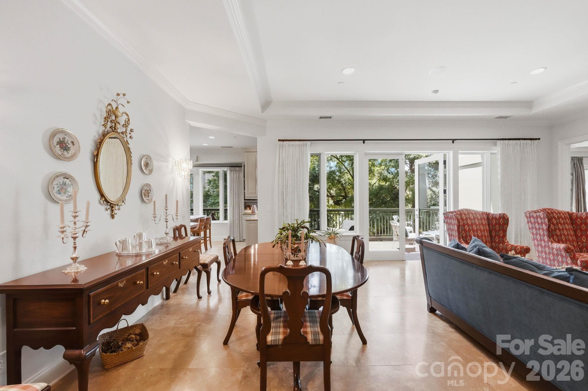 Spacious dining and living areas flow seamlessly together while oversized glass doors open to the covered terrace with peaceful treetop views in historic Fourth Ward. - Charlotte