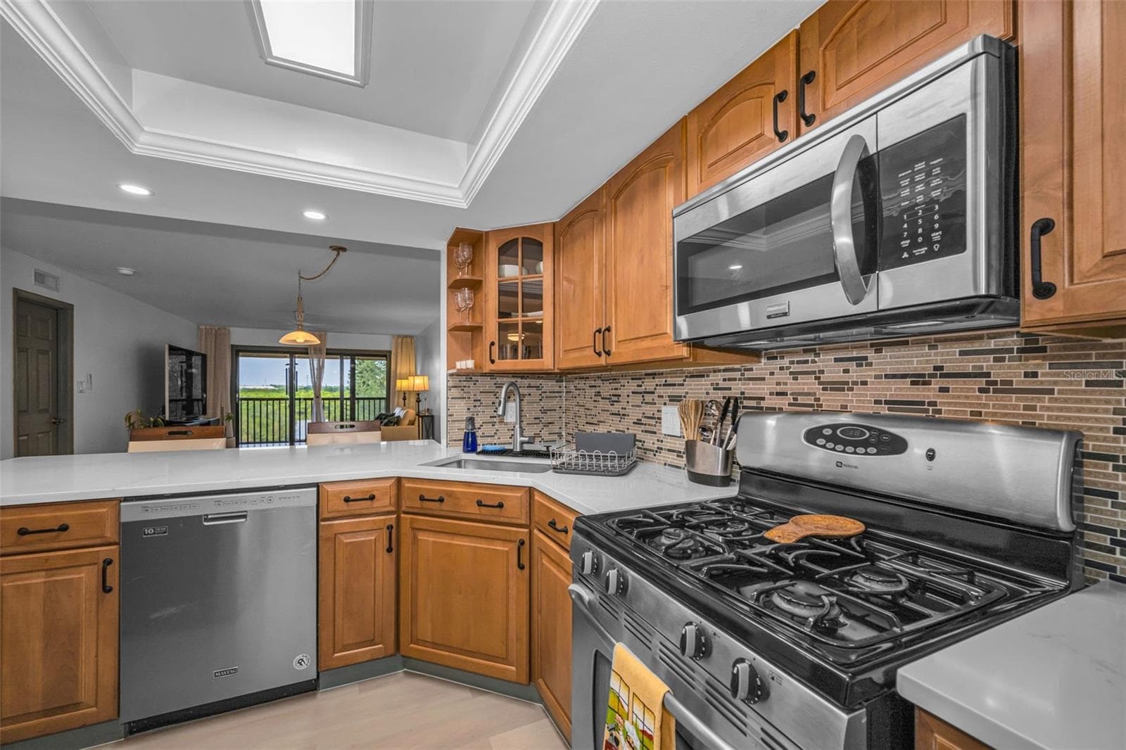 Kitchen with gas range, microwave, dishwasher, new backsplash, new overhead lighting, new Quartzite countertop. - 5400 PARK ST N #303, ST PETERSBURG