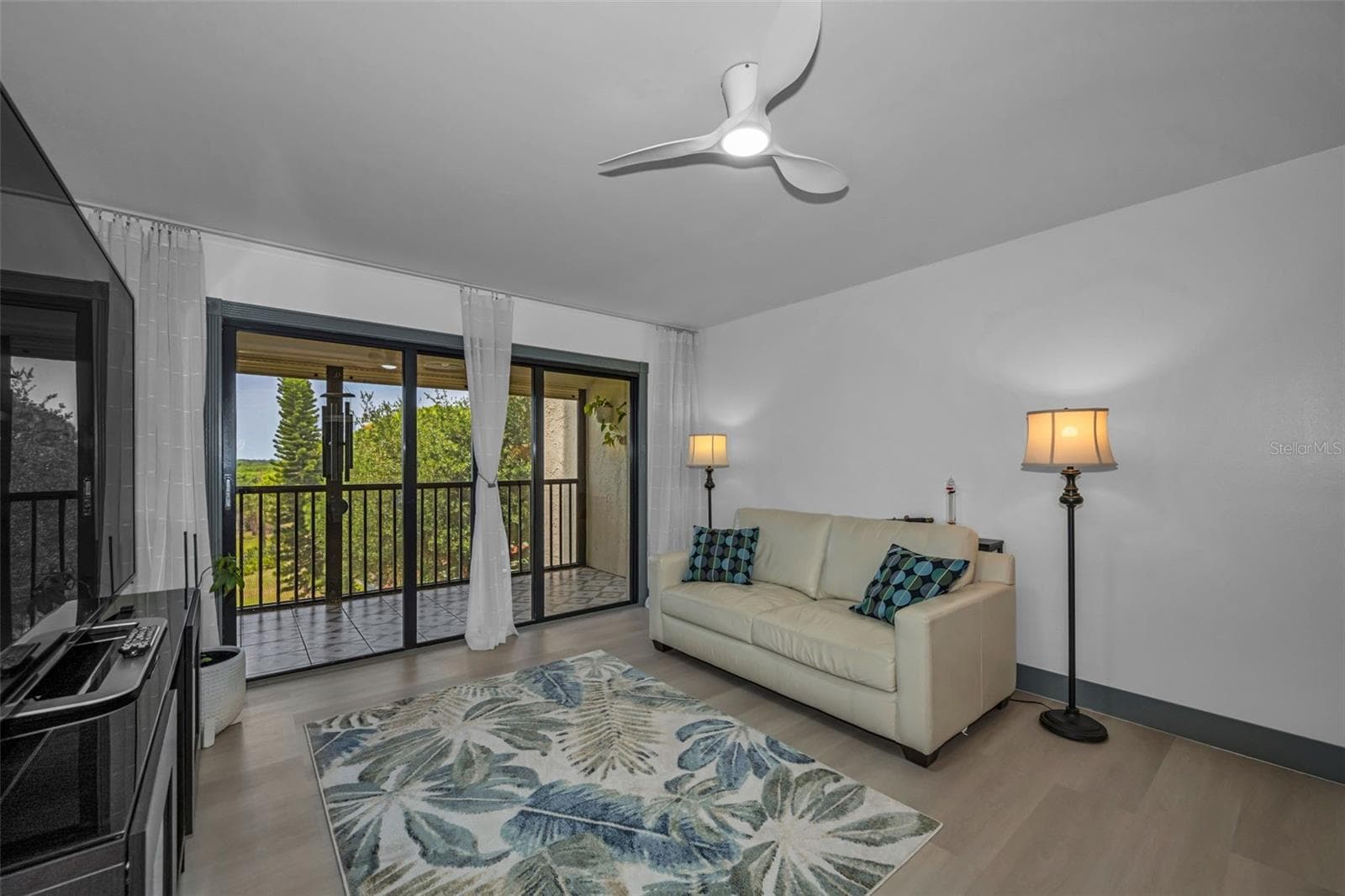 Living room with new fans view of lush landscaping from balcony. - 5400 PARK ST N #303, ST PETERSBURG