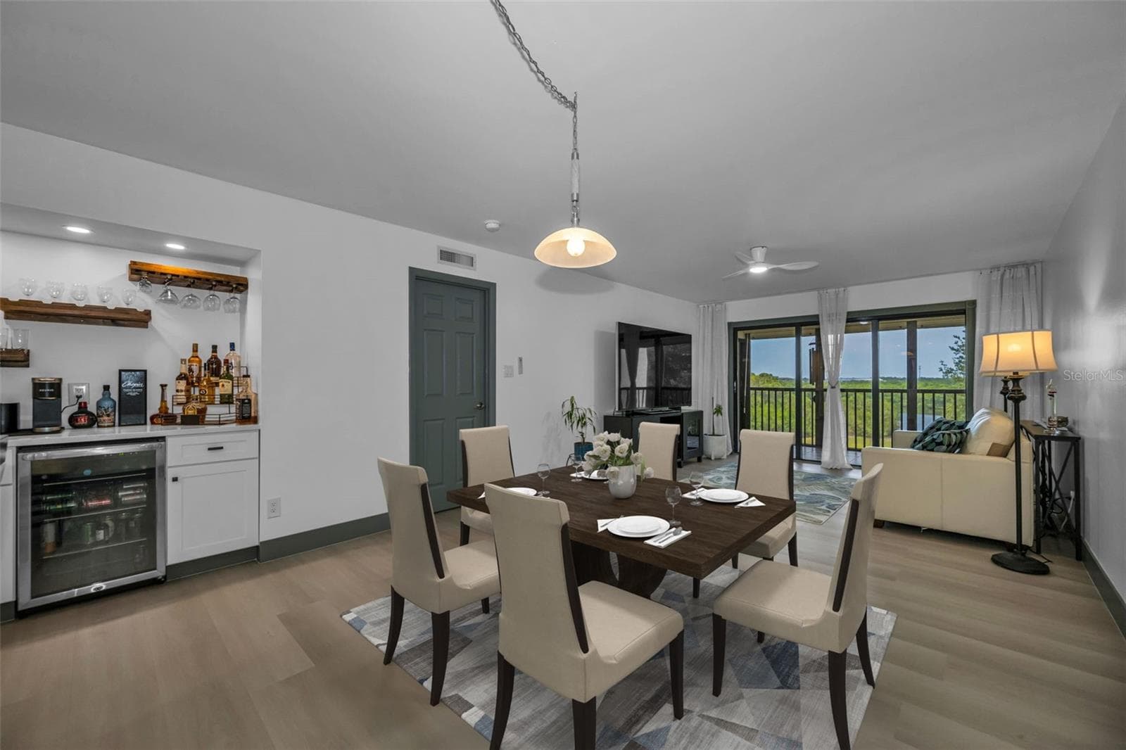 Dining room area with dry bar and wine refrigerator close at hand.  Beyond see living room and private balcony with views beyond. - 5400 PARK ST N #303, ST PETERSBURG