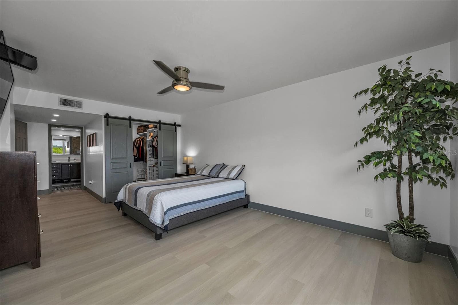 New randow vinyl plank flooring and Primary closet with cutom sliding doors. Hallway to Primary Bath. - 5400 PARK ST N #303, ST PETERSBURG