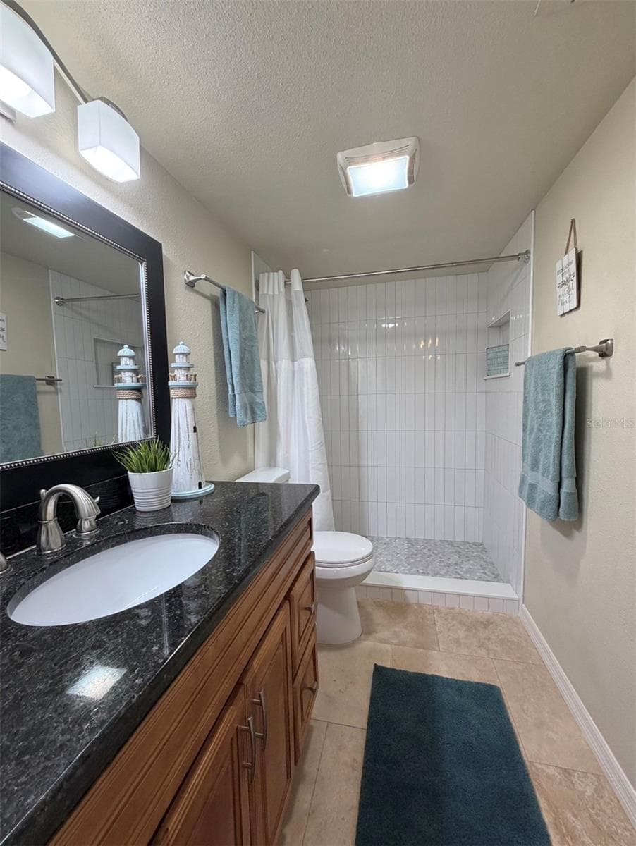 The primary ensuite features travertine floors, solid wood cabinets, granite counters, updated lighting, and an updated walk-in shower, remodeled on Oct 2025. - 3815 N OAK DR #G71, TAMPA