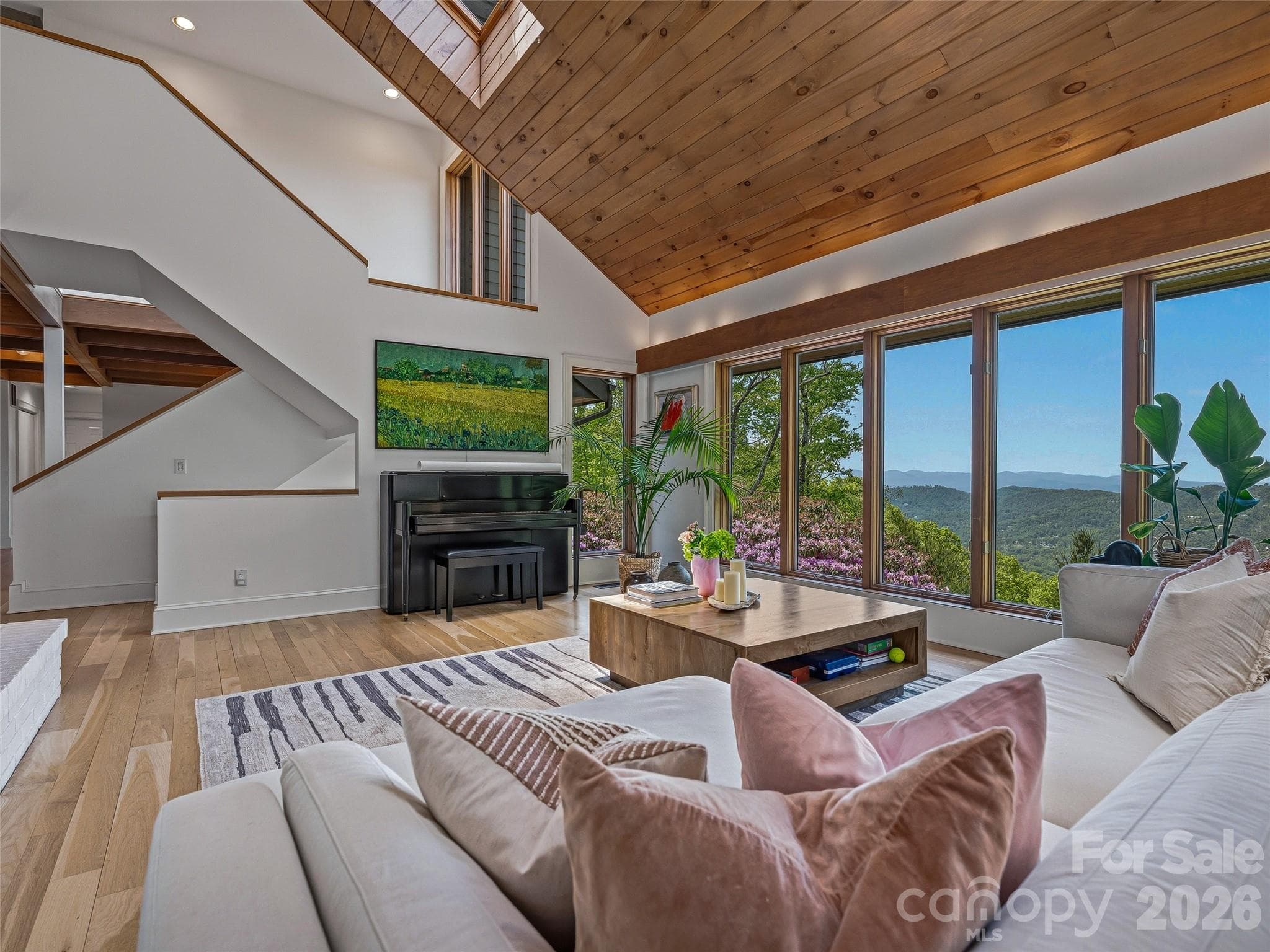 Stairs off of the great room lead upstairs to two spacious guest bedrooms and a full bath, and downstairs to an additional primary suite and large flex space that could be used as a fifth bedroom, home gym and more. - 100 Big Spring Drive, Asheville