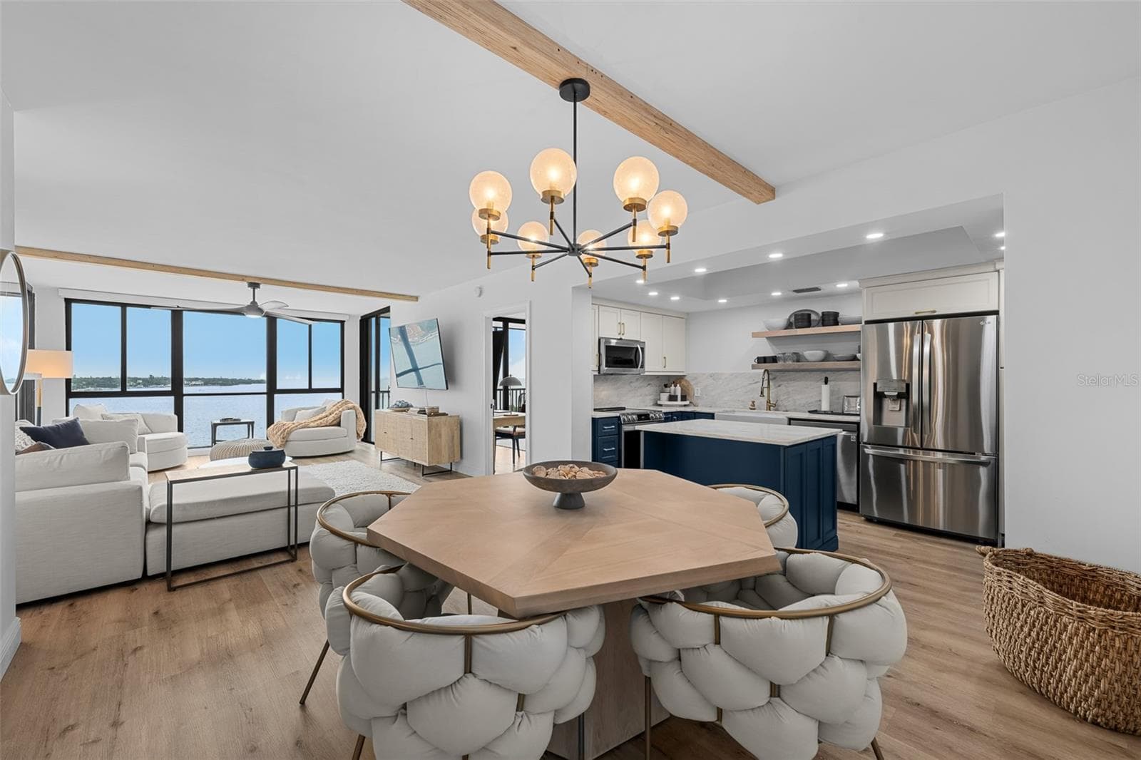 Open-concept great room with engineered hardwood flooring, exposed wood ceiling beam, and seamless flow to the dining area. - 7100 SUNSHINE SKYWAY LN S #701, ST PETERSBURG