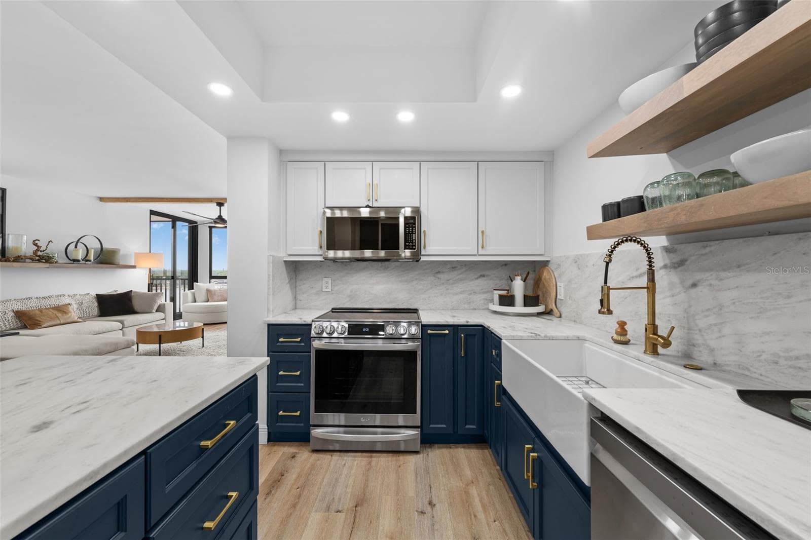 Cooking zone with LG induction range, marble backsplash, brass pull-down faucet, and open wood shelving. - 7100 SUNSHINE SKYWAY LN S #701, ST PETERSBURG